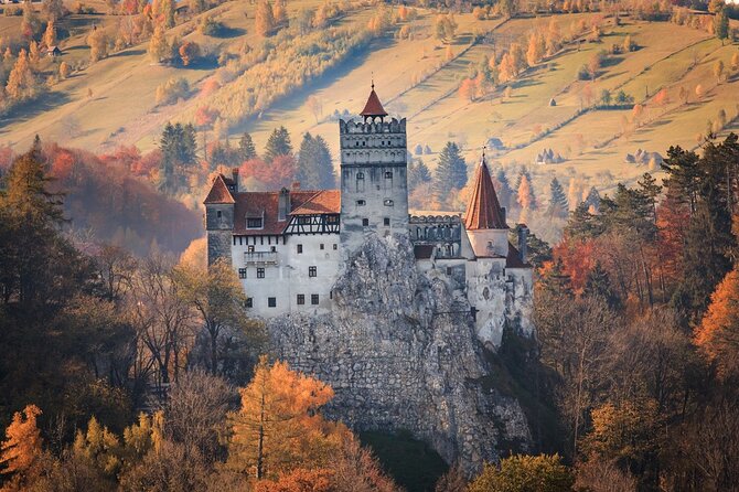 Castelul Bran înălțându-se deasupra pădurii de toamnă din Transilvania, România